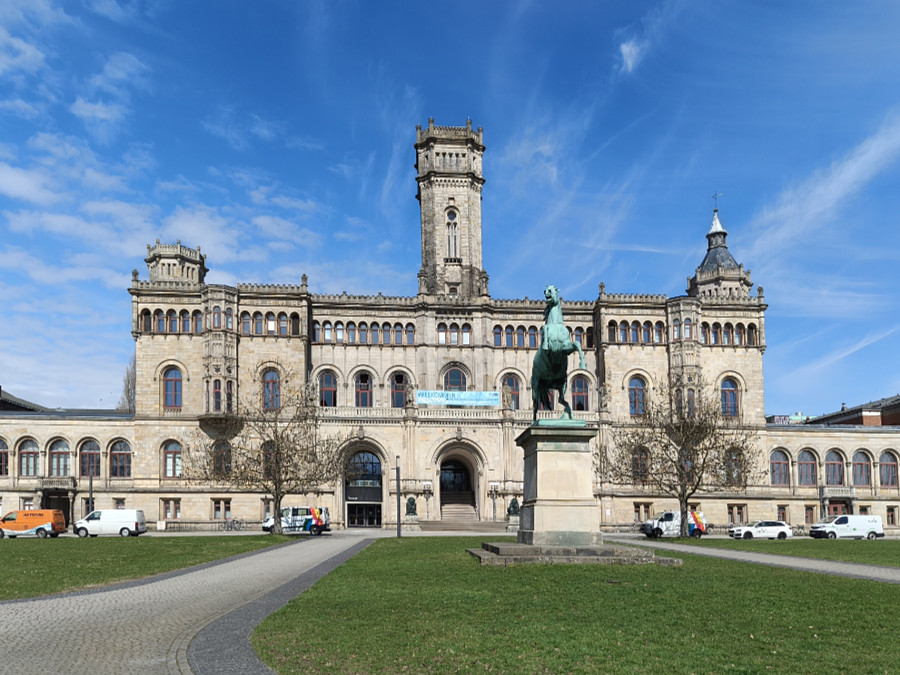 Historisches Hauptgebäude der Leibniz Universität Hannover mit Reiterstatue im Vordergrund und klarer Frühlingsstimmung.